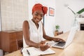 African american woman working on laptop while using phone at home Royalty Free Stock Photo