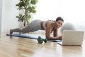 African american woman working out abdo in home livingroom gym with laptop Royalty Free Stock Photo