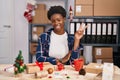 African american woman working at small business doing christmas decoration smiling with happy face winking at the camera doing