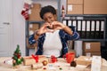 African american woman working at small business doing christmas decoration smiling in love doing heart symbol shape with hands