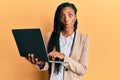 African american woman working using computer laptop making fish face with mouth and squinting eyes, crazy and comical