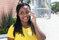 African american woman in a yellow shirt listening at mobile phone Royalty Free Stock Photo