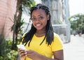 African american woman in a yellow shirt typing message with mobile phone Royalty Free Stock Photo