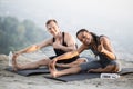 Young couple in activewear stretching legs on yoga mat