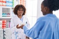 African american women pharmacist and customer paying for medicine with dollars at pharmacy