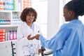 African american women pharmacist and customer paying for medicine with dollars at pharmacy