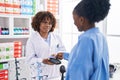 African american women pharmacist and customer paying for medicine at pharmacy