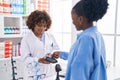 African american women pharmacist and customer paying for medicine at pharmacy