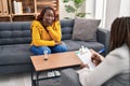 African american women psychologist and patient having mental therapy sitting on sofa at psychology clinic Royalty Free Stock Photo