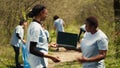 African american women use laptop with greenscreen during litter cleanup