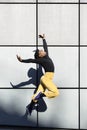 African American young adult male jumping on a wall. Dancer with 90`s look. Urban lifestyle