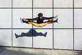 African American young adult man jumping energetically in the street. Dancer doing acrobatics in the city. Modern look, aesthetics
