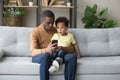 Surprised black dad and son watch video on smartphone