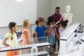 African american young male teacher showing skeleton to multiracial elementary students in lab