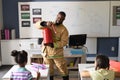 African american young male teacher in uniform showing fire extinguisher to multiracial students