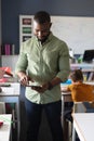 African american young male teacher using digital tablet while standing in classroom Royalty Free Stock Photo