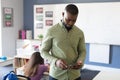 African american young male teacher using digital tablet while standing in classroom Royalty Free Stock Photo