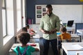 African american young male teacher using digital tablet while standing by multiracial students Royalty Free Stock Photo