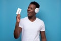 African american young man in headphones holding an old music tape.