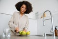 African american young woman cutting apples at kitchen in morning Royalty Free Stock Photo