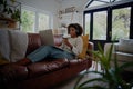 African American young woman relaxing on couch listening to music while making online payment using bank card and laptop Royalty Free Stock Photo