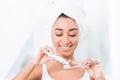 African american young woman with towel wrapped over head putting toothpaste Royalty Free Stock Photo