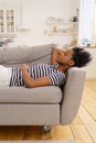 Black young woman wear stripped t-shirt resting sleeping on couch at home closed eyes taking a break Royalty Free Stock Photo