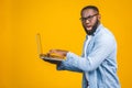 African american young man scared a bad news on his laptop, isolated against yellow background Royalty Free Stock Photo