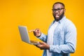 African american young man scared a bad news on his laptop, isolated against yellow background Royalty Free Stock Photo