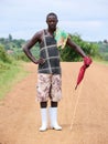 African Ankole herdsman in his work clothes holding umbrella and stick in the field