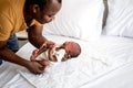 African baby black skin newborn son is 12-day-old, lying on a white bed and is crying, and African father was holding him Royalty Free Stock Photo