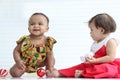 African baby kid colorful dress and her friend in red costume in white room with decorative Christmas ornament items. Two cute Royalty Free Stock Photo