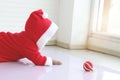 African baby kid in red Santa Claus costume crawling to grab ball ornament in white living room, beautiful little child girl