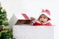 African baby kid in Santa Claus red costume standing in big gift box present at white room, beautiful little child celebrates