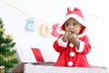 African baby kid in Santa Claus red costume standing in big gift box present at white room, beautiful little child celebrates