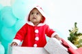 African baby kid in Santa Claus red costume standing in big gift box present at white room, beautiful little child celebrates