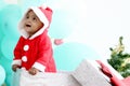 African baby kid in Santa Claus red costume standing in big gift box present at white room, beautiful little child celebrates