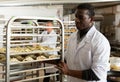 African baker carrying formed raw products on trolley