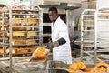 African baker pulling loaves from oven