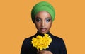 African beautiful girl in a colored headscarf on her head holding flowers in her hand