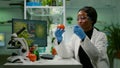 African biochemist with medical gloves injecting organic tomato with pesticides