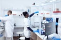 African in biotechnology laboratory reaching for glass flask