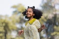 African black child with curly hair is jumping happily in the water spray at outdoor