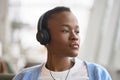 African Black generation z girl with short hair sitting wearing headphones.