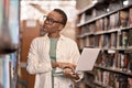 African Black girl student using laptop standing in college library. Royalty Free Stock Photo