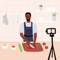 African black male chef cooking in the kitchen while recording video using his camera for online video channel. Cook healthy food