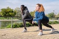 African black man and redhead caucasian woman stretching their legs in a park