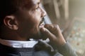 African black man using tablet on sofa couch in home living room. Closeup portrait. Flare.