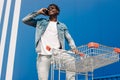 African black man walking with a shopping cart talking on the phone, making a phone call Royalty Free Stock Photo