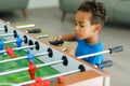 An African boy is having fun playing table football in a children's play entertainment center. Hobby and leisure Royalty Free Stock Photo